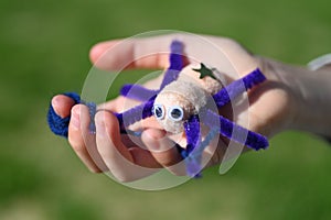 Child hand carry a handmade toy spider