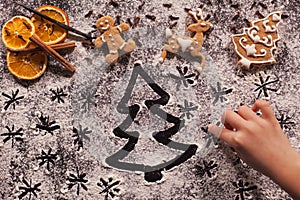 Child hand drawing holidays scene in the flour prepared for the