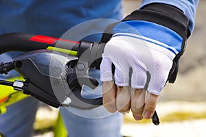 Child hand with glove on handlebars with brake lever.