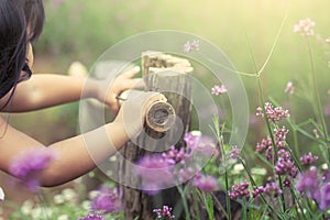 Child hand holding bamboo railing in the flower garden