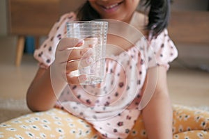 child hand holding a glass of water