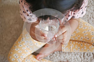 child hand holding a glass of water