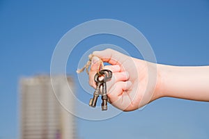 Child hand holding an old keys to the house against the sky