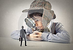 Child with a hand lens looking at a businessman