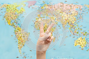 Child hand making Peace sign on world map background.  Peaceful life all over the world concept