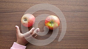 child hand pick apple on table