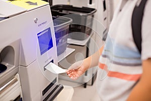 The child hand is picking up the receipt from the automatic payment machine. self service machine in modern supermarket, self-
