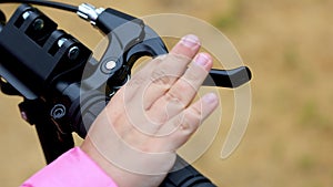 Child hand pressing brake on a scooter.