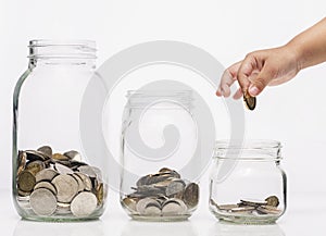 Child hand putting a coin into glass bottle, future saving concept