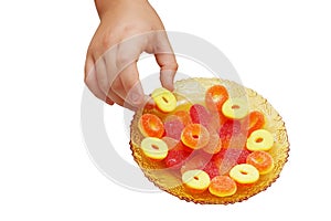 Child hand take a candy from a saucer with candies