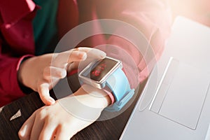 Child hand wearing smart watch. Wearable gadget concept. Little boy using smart watch while siting at the table and working with