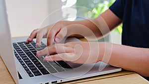 Child hands close up typing on laptop keyboard