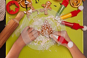 Child hands decorate christmas gingerbread cookies - top view