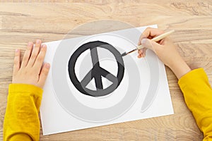 Child hands drawing Peace sign with paint and brush. World peace concept