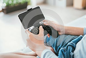 Child hands with game controller connected with smartphone. Electronic devices and technology concept