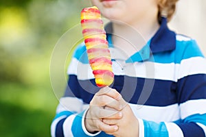 Child hands holding colorful fruit ice cream.