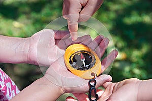 Child hands holding a compass in a geocaching game. Outdoor sport in the nature with empty copy space