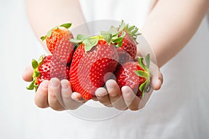 Child hands holding fresh ripe strawberries