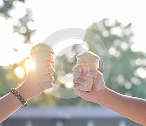 Child hands holding ice cream cone on summer light nature background