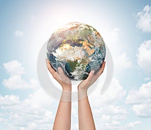 Child hands holding planet earth over sky background