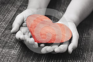 Child hands holding red heart