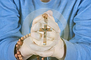 Child Hands holding rosary beads and cross while praying