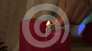 Child hands lighting candles with match, fire safety at Christmas time, closeup