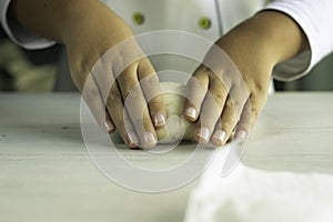 Child hands making bread with fresh dough on wooden board photo