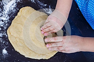 Child hands are making cookies.