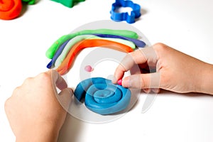 Child hands molding modeling clay or plasticine on white table