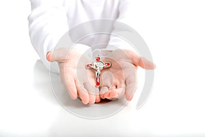 Child hands offer red and silver cross