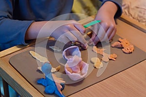 Child hands playing with colorful baby play dough, plasticine