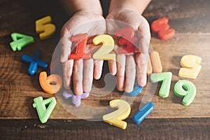 Child hands showing a colorful 123 numbers agains wooden table