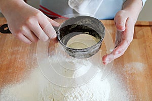 Child hands sifted flour.