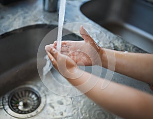 Child, hands and washing for clean hygiene, health and wellness with water in the kitchen. Hand of kid rinsing or