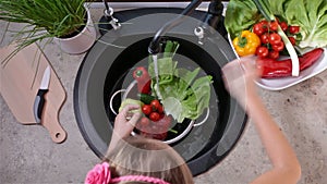 Child hands washing lettuce leaves