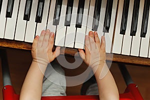 Child hands on a white piano key