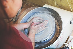 Child hands working with clay on pottery wheel