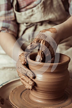 Child hands working on pottery wheel at workshop