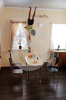 Child hanging up side down in kitchen
