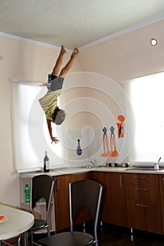Child hanging up side down in kitchen