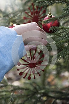 Child hangs a Christmas toy snowflake on the Christmas tree, Christmas