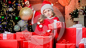 Child happy excited girl find gifts near christmas tree. Merry christmas. Kid wear santa hat hold wrapped christmas gift