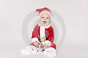 Child happy girl in Santa hat on white background with Christmas ball. Kid having fun at Christmas time. Merry Xmas concept