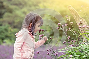 Child happy little girl smelling flower in the garden