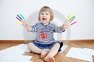 Child happy smiling sitting on floor playing with felt tip pens. baby girl painting and playing. colorful stuff felt pen caps