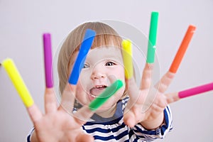 Child happy smiling sitting on floor playing with felt tip pens. baby girl painting and playing. colorful stuff felt pen caps