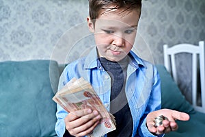 the child has a lot of money in one hand and small coins in the other hand