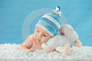 Child in hat hugging toy on a white bedspread