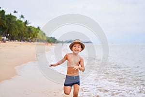 A child in a hat runs and smiles - Asian boy in a hat, blurred background